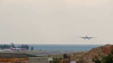 PHUKET, THAILAND - JANUARY 29, 2023: Panoramic view of the runway. Aircraft landing, front view. Passenger flight arrival in Phuket. Row of plane in queue for departure.