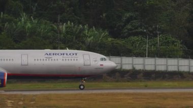 PHUKET, THAILAND - JANUARY 29, 2023: Commercial airplane of Aeroflot taxiing at Phuket Airport, side view. Passenger jet riding on the taxiway. Airfield on a tropical island