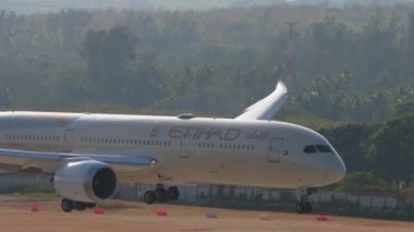 PHUKET, THAILAND - FEBRUARY 08, 2023: Geniş gövdeli yolcu uçağı Boeing 787 Dreamliner, Etihad Havayolları 'nın A6-BNC' si, Phuket havaalanına iniyor, dokunuyor, fren yapıyor. Kanatçıklar yukarı, hız aşağı.