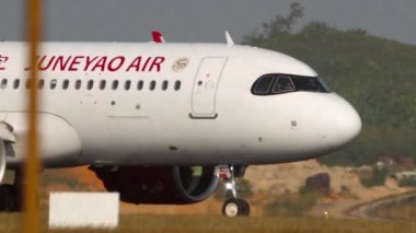 PHUKET, THAILAND - 20 Şubat 2023: Airbus A320-271N, B-324U Juneyao Havaalanı 'nda taksicilik. Havaalanının çitlerinden uçağın görüntüsü. Hava trafiği, havaalanı