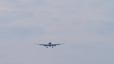 Jet uçağı inişe geçiyor. Uçak sinekleri, mavi gökyüzü arkaplanı. Uçak silueti iniyor, geniş açılı görüş. Seyahat kavramı