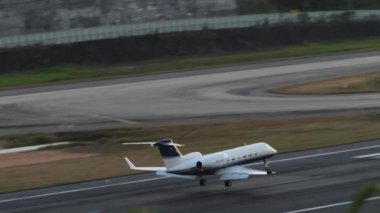 PHUKET, THAILAND - 11 Şubat 2023: Özel jet Gulfstream G450 Alpi Jets 'in Phuket havaalanına iniş ve fren yapması uzak ihtimal. Küçük iş jeti piste iniyor. Turizm ve seyahat kavramı