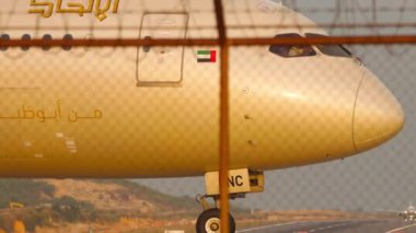 PHUKET, THAILAND - 20 Şubat 2023: Boeing 787-9 Dreamliner, Etihad Havayolları 'nın A6-BNC' si Phuket Havaalanı 'ndaki havaalanında taksicilik yapıyor. Yakın plan, uçak gün batımında takside.
