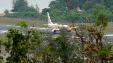 PHUKET, THAILAND - 28 Kasım 2017: Nok Air 'in Boeing 737' si Phuket havaalanından kalkmadan önce hızlandı. Denizin arka planındaki havaalanı. Turizm ve seyahat kavramı