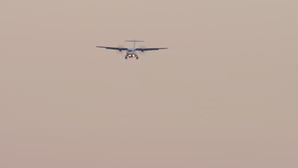 着陸に近づいてターボプロップ機のフロントビュー 飛行機の降下 日没または夜明け 航空機のハエ — ストック動画