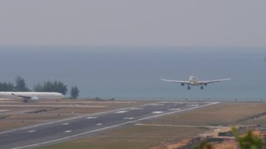 PHUKET, THAILAND - 13 Şubat 2023: Jet Yolcu Airbus A330-302, Katar Havayolları 'nın A7-AEF' i, Phuket havaalanına iniş ve frenleme. Denizin arka planı. Turizm ve seyahat kavramı