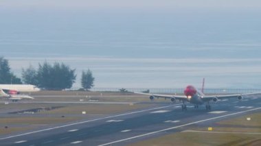 PHUKET, THAILAND - 23 Şubat 2023: Airbus A340, Edelweiss Air 'den HB-JME Phuket havaalanına indikten sonra fren yapıyor. Flaplar yukarı. Uçak iniyor. Havaalanındaki diğer uçaklar. Deniz kıyısındaki havaalanında.