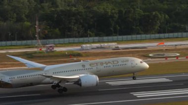 PHUKET, THAILAND - 11 Şubat 2023: Etihad Havayolları 'nın Boeing 787 Dreamliner uçağı Phuket havaalanına iniş ve dokunuş, yan görüş. Jet modern uçaklar geliyor. Turizm ve seyahat kavramı