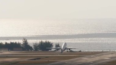 Uçak kalkıyor ve Phuket Havaalanı 'na tırmanıyor. Uçak kalkıyor. Uçak denizin üzerinde uçuyor. Turizm ve seyahat kavramı
