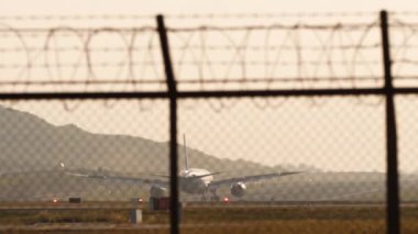 İniş uçağı arka planda. Uçak silueti gün batımında denizin arka planında fren yapıyor. Arka planda bir jet uçağının sinematik çekimi. Turizm ve seyahat kavramı