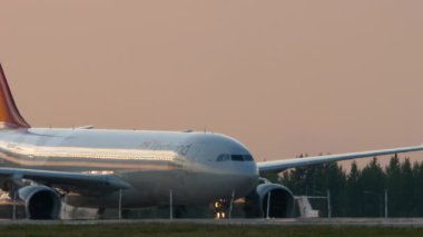 KAZAN, RUSSIA - 05 AĞUSTOS 2022: Sivil uçak Airbus A330 Nordwind, gün batımı veya gündoğumu arka planı. Yolcu panosu havaalanının taksisinde. Turizm ve seyahat kavramı