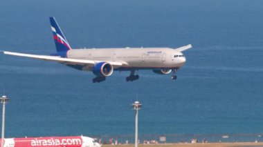 PHUKET, THAILAND - 20 Şubat 2023: Aeroflot 'un Boeing 777' si, Phuket Havaalanı 'na iniş ve frenleme. Uçak geliyor, yan görüş. Okyanusun arka planında bir uçak