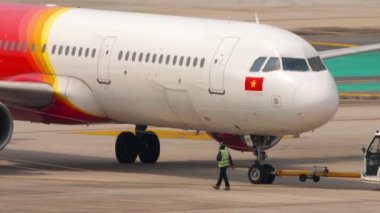 PHUKET, THAILAND - 25 Şubat 2023: traktör ve uçak havaalanında. Vietnam JetAir 'in Jet uçağı Phuket Havaalanı' ndaki terminalden kalkıyor. Uçak havalanmaya hazır. Turizm ve seyahat kavramı