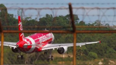 PHUKET, THAILAND - FEBRUARY 05, 2023: AirAsia 'nın Phuket Havaalanı' na iniş ve frenleme görüntüleri. Flapları kapat, fren yap. Uçak varmak üzere. Asya 'da ucuz havayolu. Uçuş. Airbus A320