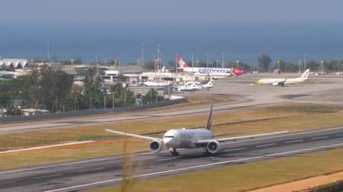 PHUKET, THAILAND - 23 Şubat 2023: Yolcu uçağı Boeing 777 Emirates 'in Phuket havaalanından kalkış görüntüleri. Yan görüş, geniş gövdeli uçak ayrılıyor, tırmanıyor. Turizm seyahati kavramı