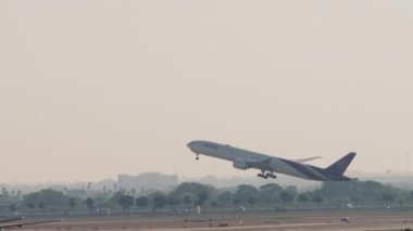 BANGKOK, THAILAND - 21 HAZİRAN 2023: Suvarnabhumi Havalimanı 'ndan kalkan Boeing 777. Uçak sisli ve arka planda uçar. Geniş gövdeli uçaklar tırmanıyor.