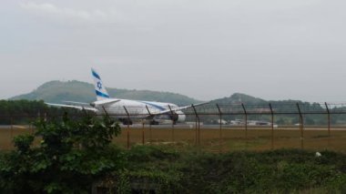 PHUKET, THAILAND - 31 Ocak 2023: El Al 'in Boeing 787 Dreamliner' ı Phuket Havaalanı pistinde. Havaalanı çitlerinin arkasındaki uçak. El Al Havayolları İsrail. Turizm ve seyahat kavramı