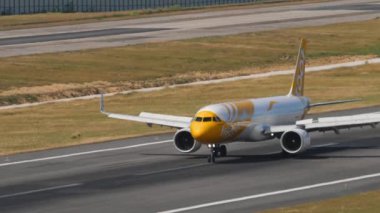 PHUKET, THAILAND - FEBRUARY 07, 2023: Airbus A321, 9V-NCD Scoot, Phuket Havaalanı 'na indikten sonra fren yapıyor. Taksiyoldaki uçak, yan görüş. Uçak sürüşünün görüntüsü. Beneklenme