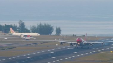 PHUKET, THAILAND - 23 Şubat 2023: Yolcu jet uçağı A340, Edelweiss Havaalanı HB-JME ve Phuket Havaalanı 'na fren. Flaplar yukarı. Uçak iniyor. Havaalanının panoramik görüntüsü
