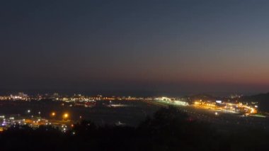 Gece havaalanı pisti, zaman aşımı. Uçak kalkış ve inişler, trafik. Havaalanı ve şehrin panoramik manzarası. Turizm ve seyahat kavramı