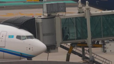 PHUKET, THAILAND - 25 Şubat 2023: Yolcu teleskopik köprüde indi. İskeledeki uçak, insanları terk et. SCAT Havayollarından Boeing 737 MAX Phuket havaalanına varıyor..