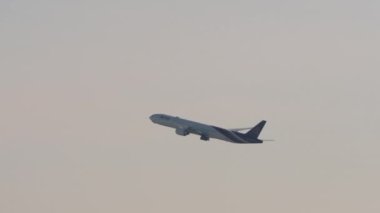 BANGKOK, THAILAND - 21 HAZİRAN 2023: Suvarnabhumi Havaalanı 'ndan kalkan yolcu uçağı yan görüntüsü. Uçak sisli ve arka planda uçar. Geniş gövdeli uçaklar tırmanıyor.