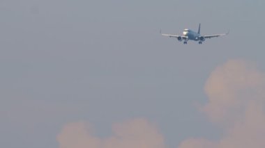 İniş yapan bir jet yolcu uçağı görüntüsü. Gökyüzü bulutlu, havada uçan bir uçağın uzun bir görüntüsü. Turizm ve seyahat kavramı