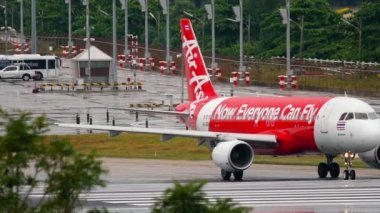 PHUKET, THAILAND - DECEMBER 02, 2016: Airbus A320 AirAsia on runway before takeoff at Phuket Airport. Rainy day, wet airfield. Tourism and travel concept