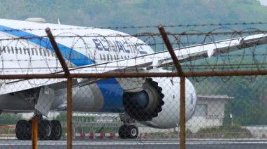 PHUKET, THAILAND - 31 HAZİRAN 2023: Pistte taksicilik yapan El Al 787 numaralı uçak. Havaalanı çitlerinin arkasındaki uçak. Dikenli tel