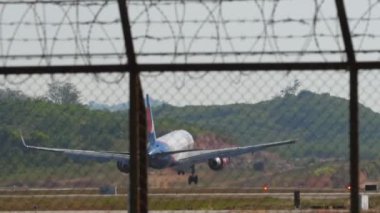 PHUKET, THAILAND - 10 Şubat 2023: Azur Air 'in sivil uçağı Phuket Havaalanı' na iniş ve frenleme, çitin arkasından arka görüş. Turizm seyahati kavramı