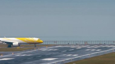 PHUKET, THAILAND - FEBRUARY 03, 2023: Airbus A321, Scoot havaalanındaki pistte taksicilik yapan 9V-NCJ. Singapurlu ucuz havayolu şirketi. Denizin yanındaki havaalanı.