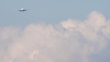 Jet yolcu uçağı güneşli bulutlu gökyüzüne inmek üzere yaklaşıyor. Tanınamayacak kadar yüksek bir uçak gökyüzünde