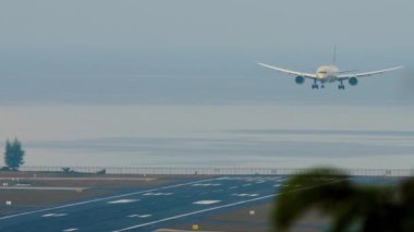Sivil uçak iniş için yaklaşıyor, ön görüş. Denizin arka planındaki havaalanı. Tropik ada, havaalanı