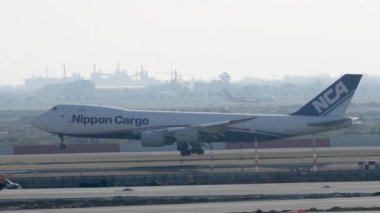 BANGKOK, THAILAND - 21 HAZİRAN 2023: Suvarnabhumi Havalimanı 'na iniş ve frenleme yapan Nippon Kargo Havayolları' nın Jumbo jet 747 'si. Yan görüş, kargo gemisi uçakları.