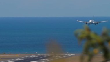 Uçaklar denizden havaalanına iniyor. Mavinin üzerine inen ticari uçağın görüntüsü. Uçaklar adaya uçuyor. Turizm ve seyahat kavramı