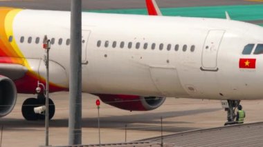 PHUKET, THAILAND - 25 Şubat 2023: uçak havaalanı pistine geri itiliyor. Phuket havaalanında traktör yolcusu Viet Jet. Uçuş öncesi havacılık servisi.