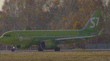 NOVOSIBIRSK, Rusya Federasyonu - 20 Ekim 2021: Airbus A320, Tolmachevo Havaalanı OVB 'de taksicilik yapan S7 havayolları VQ-BCH. Sonbahar ormanının arka planında bir uçak.