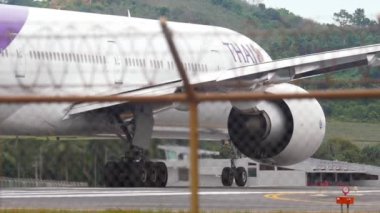 PHUKET, THAILAND - 05 Aralık 2016: Tayland Havayolları 'ndan Boeing 777 sefer sayılı yolcu uçağı, Phuket Havaalanı, çitin ardından görülmektedir. Turizm ve seyahat kavramı