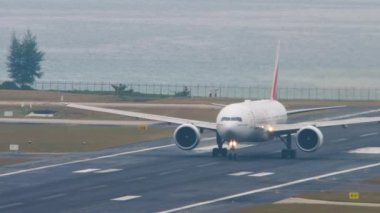 PHUKET, THAILAND - Şubat 03, 2023: Yolcu uçağı Boeing 777 Emirates Phuket havaalanından havalanır. Geniş gövdeli uçak kalkışı, orta atış. Turizm ve seyahat kavramı