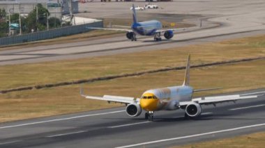 PHUKET, THAILAND - FEBRUARY 07, 2023: Airbus A321, Phuket Havaalanına indikten sonra Scoot frenleme 9V-NCD. Taksiyoldaki uçak, yan görüş. Uçağın görüntüsü geldi. Flaplar yukarı, yavaşlama.