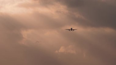 Gün batımının muhteşem ışığında uçan uçak, dramatik bulutlarda uçan yolcu uçağı. Seyahat ve Turizm Konsepti