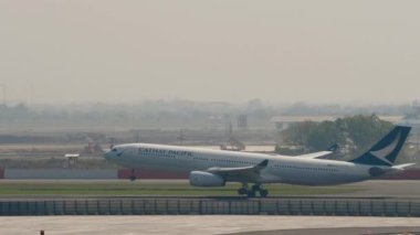BANGKOK, THAILAND - 01 Mart 2023: Airbus A330-343, B-LAZ Cathay Pasifik iniş ve frenleme Suvarnabhumi Havaalanı, yan görüş. Bir uçağın gelişinin sinematik görüntüleri.