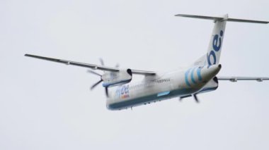 AMSTERDAM, NETHERLANDS - 24 Temmuz 2017: Bombardıman uçağı DHC-8-400, Flybe C-FVUV Amsterdam Havaalanı 'nda mavi gökyüzünde uçuyor. Turizm ve seyahat kavramı