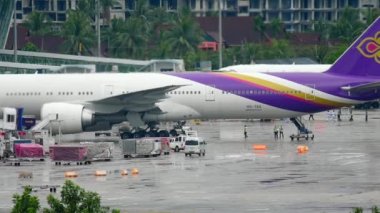 PHUKET, THAILAND - DECEMBER 02, 2016: Boeing 777 of Thai Airways at the terminal at Phuket Airport. Rainy day, wet airfield. Tourism and travel concept