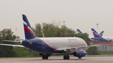 MOSCOW, Rusya Federasyonu - 28 Temmuz 2021: Ticari uçak Sukhoi Superjet 100, Aeroflot 'tan RA-89041 Sheremetyevo havaalanı, yan görüş, orta çekim. Havaalanında sıra sıra bekleyen uçaklar.