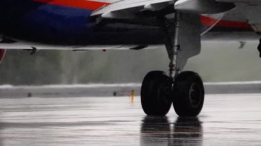 Chassis yakın plan, ıslak pist. Sağanak yağış altında uçak kalkıyor. Uçak iniş takımları, yan görüş. Turizm ve seyahat kavramı
