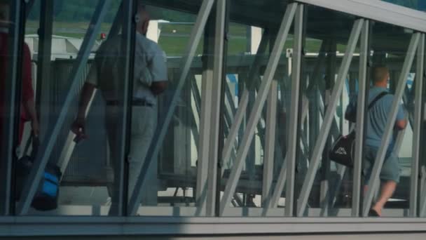 モスクワ ロシア連邦 2021年7月28日 ガラス伸縮橋を通って飛行機に搭乗する人々 望遠のギャングウェイ スリーブ 空港の飛行機のエアロビクスリッジ — ストック動画