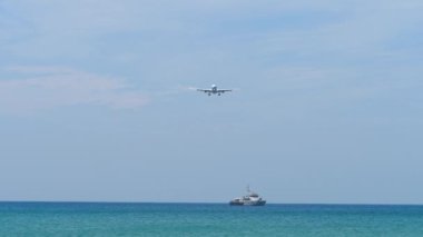 Ticari yolcu uçağı iniş pisti, alçalın. Mavi denizde seyreden bir geminin panoraması. Uçak onun üzerinden uçuyor.