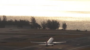 Jet uçağı gün batımında denizin üzerinde uçar. Tatil, havacılık, seyahat, gezi konsepti, fotokopi alanı. Modern ticari uçaklar kalkıyor, okyanusa tırmanıyor, arka planda güzel bir günbatımı var..
