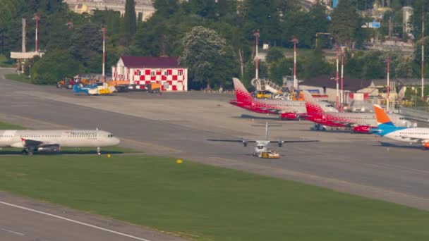 ロシア 2022年7月29日 トラクター ジェット機Atr Utair がソチのアドラー空港の滑走路を長距離射撃した 航空機の行は ドッキング駐車した 北風が待っている 旅行のコンセプト — ストック動画